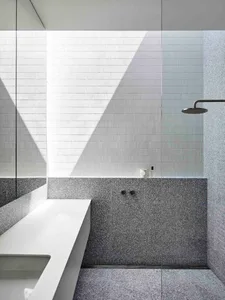 A modern minimalist bathroom with textured terrazzo tiles on the shower wall and floor.