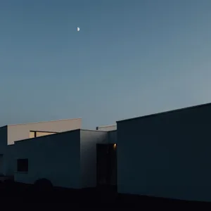 Minimalist-style exterior of a modern building with a crescent moon in the sky.