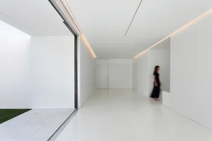 Minimalist white marble interior with a person walking through the hallway.