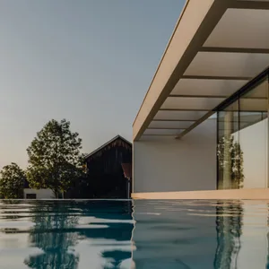 Modern architectural design featuring a glass poolside and minimalist structure.