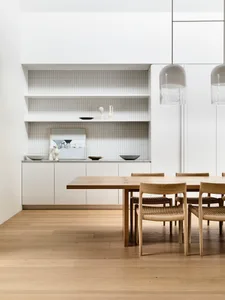 A contemporary dining room with a wooden table and marble decorations.