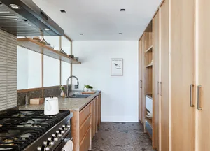 Modern kitchen featuring minimalist design with wood cabinetry and marble countertops.