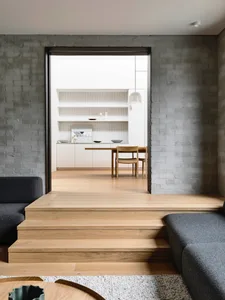 Modern living room featuring a concrete wall, wooden steps, and grey fabric furniture.