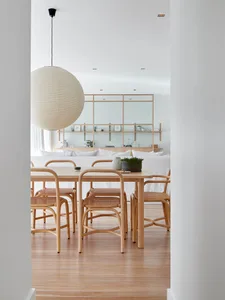 Minimalist dining room with wooden furniture and a spherical pendant light.