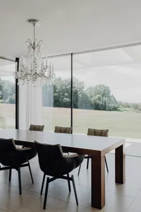 Modern minimalist dining room with a wooden table and black chairs.