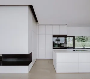 A modern minimalist kitchen featuring white cabinets and glass elements