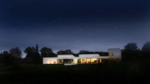 A modern, minimalist residential building with large glass windows and a white exterior at night with a starry sky.