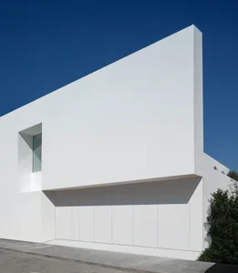 White concrete building facade with minimalist design and a large window.