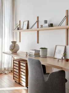 A modern workspace with a wooden desk and shelves, featuring a comfortable grey chair.