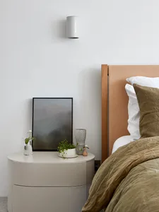 A minimalist bedroom featuring a wood headboard and neutral color scheme.