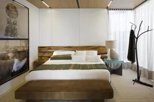 Modern bedroom featuring a minimalist design with a wooden platform bed, white bedding, and a green throw blanket.