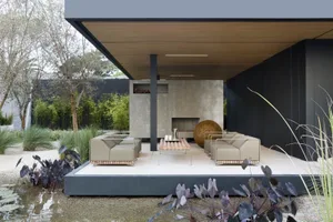 A modern outdoor lounge area featuring a concrete sofa and coffee table, set against a natural backdrop.