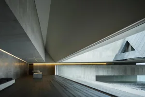 An industrial-style interior with exposed concrete walls and floor, featuring minimalist design and modern furnishings.