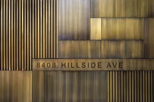 An architectural detail showing metallic brass signage with the address '8408 Hillside Ave'.