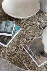 A granite tabletop with a porcelain bowl, ceramic vase, and books arranged meticulously for interior decoration.
