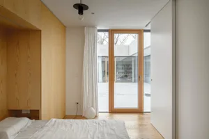 A minimalist bedroom with wooden furniture and a glass door.