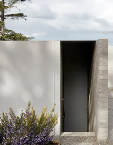 Modern, minimalist house exterior with a concrete wall and metal door.
