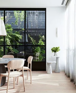 A minimalist dining room featuring wooden chairs and a marble table, surrounded by large windows.
