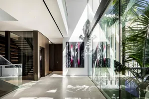 Modern Art Deco hallway featuring large glass walls, concrete flooring, and contemporary art pieces.