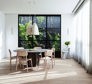 A modern dining room featuring wooden furniture, a round table, and large windows with greenery outside.