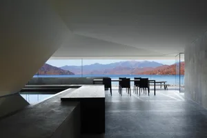 A modern interior featuring concrete walls and glass windows overlooking a scenic landscape.