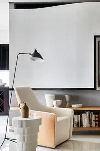 A modern living room featuring a fabric and leather armchair, a concrete side table, and a black floor lamp.
