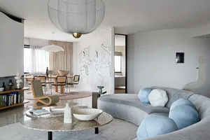 Modern living room featuring a sculptural sofa with round cushions, a round marble coffee table, and a large abstract mural o
