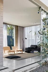 A modern minimalist living room with concrete flooring and floor-to-ceiling windows.