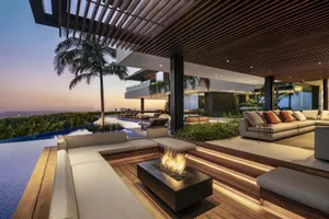 Contemporary residential outdoor area with lounge seating, fire pit, pool, and palm tree.