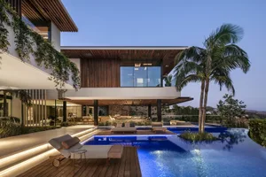 Modern residential pool house featuring a luxurious lounge area with a poolside seating arrangement, surrounded by a combinat