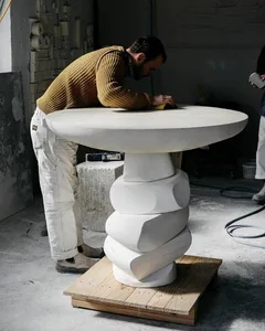 A person in a yellow sweater working with concrete in a workshop setting.