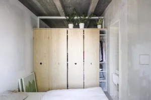 A minimalist bedroom with an open wooden closet