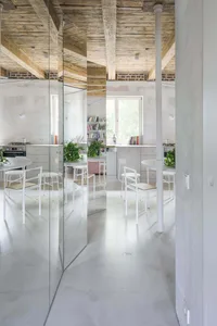 A minimalist industrial kitchen with a white concrete ceiling and modern furniture.