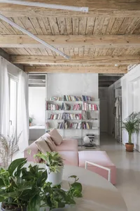 Minimalist living room with glass shelves, concrete flooring, and pink upholstered furniture.