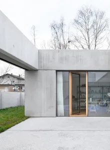 Concrete residential extension with glass windows and open floor plan.