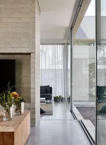 Modern living room with glass walls, concrete flooring, and minimalist furniture.