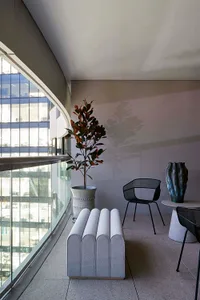 Modern minimalist living space featuring metal and glass furniture with concrete flooring.