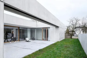 A modern residential building with a concrete façade and large glass windows.