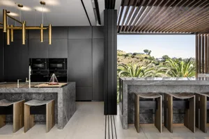 Modern residential kitchen featuring marble countertops and bar stools.