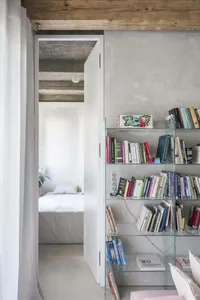 A modern bedroom featuring concrete walls, glass shelves, and minimalist furniture.