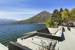 Concrete terrace overlooking a lake with a mountain in the background.