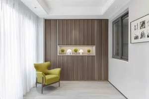 A modern entryway featuring wooden shelving with decorative items and a green armchair.