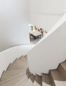 Modern staircase with white railings and wooden steps leading to a dining area.