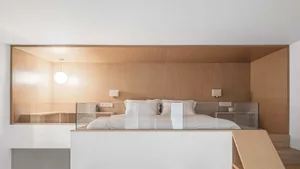 A minimalist bedroom with wooden elements, including a bed, nightstands, and a ceiling.