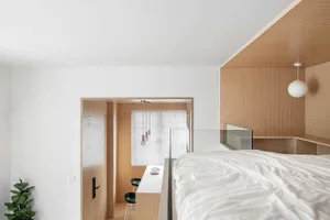 A minimalist bedroom with wooden walls and white bedding.