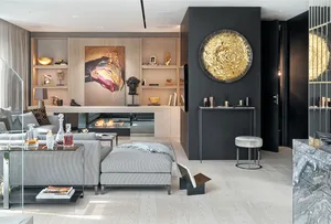 A modern minimalist living room with a gray sectional sofa, a glass coffee table, and a sleek fireplace with a golden decorat