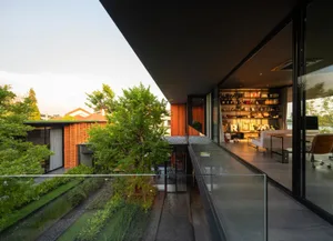 A minimalist residential exterior with a green roof, incorporating glass, wood, and concrete materials.