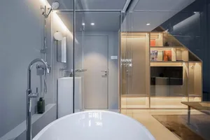 A modern bathroom featuring transparent glass walls and a large freestanding bathtub.