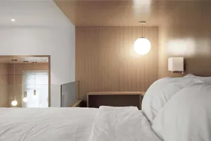 A modern bedroom with a wooden wall, white bedding, and minimalist style