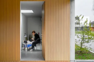 A ceramic artist sits at a workbench in a modern studio with industrial design elements, surrounded by wooden panels and natu